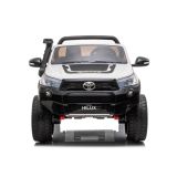 Niño conduciendo el coche eléctrico Toyota Hilux en el jardín con amigos